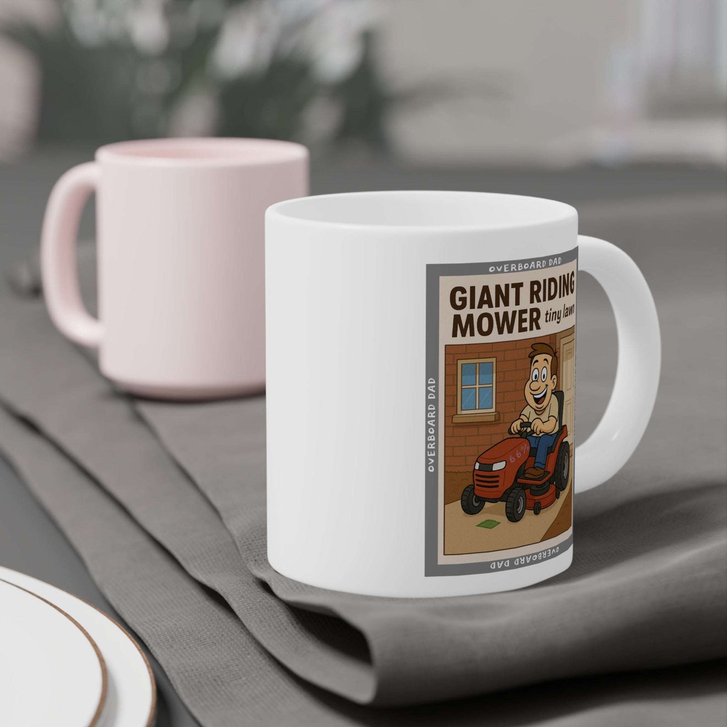 Humorous dad gift mug—white ceramic mug showing a bearded father on an oversized riding mower cutting a tiny strip of grass, ‘Overboard Dad’ top and bottom