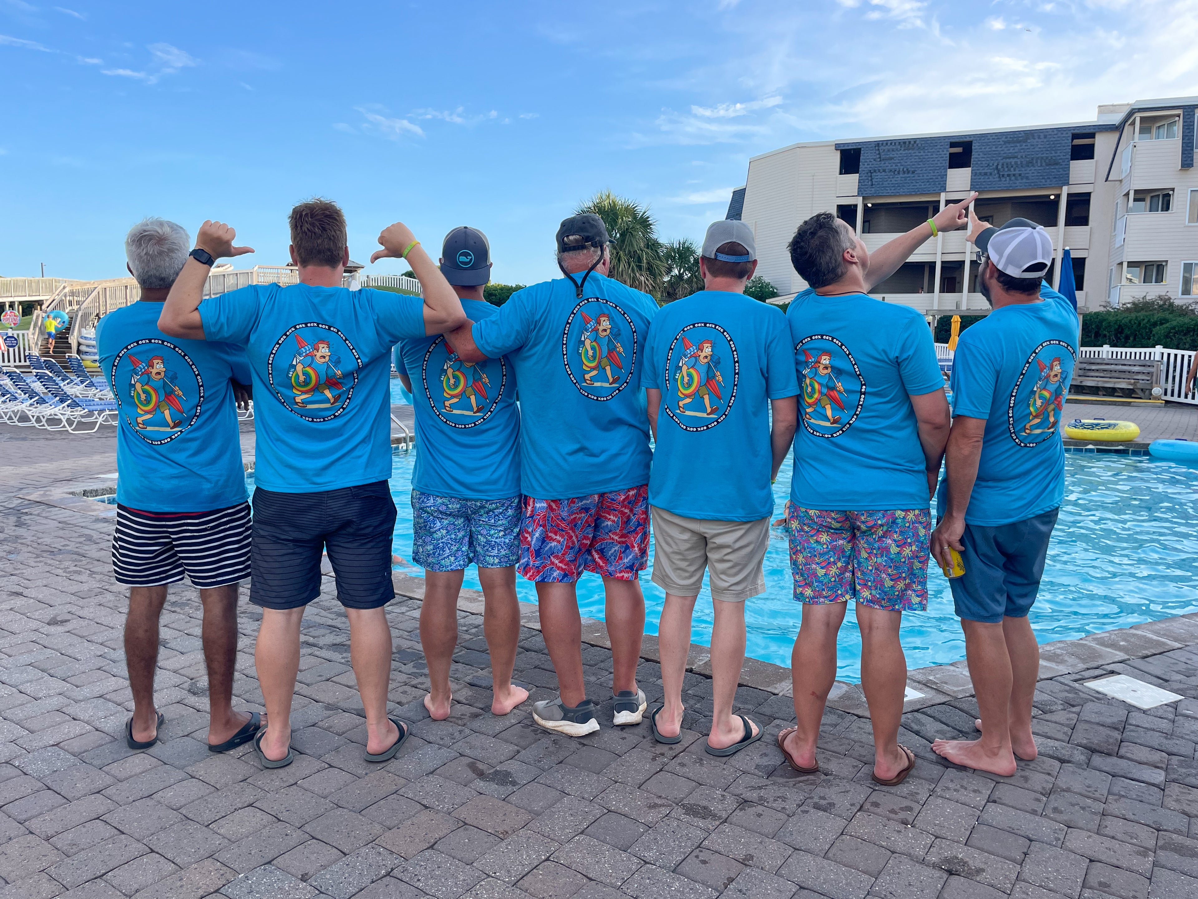Group of men wearing matching blue t-shirts by a poolside.