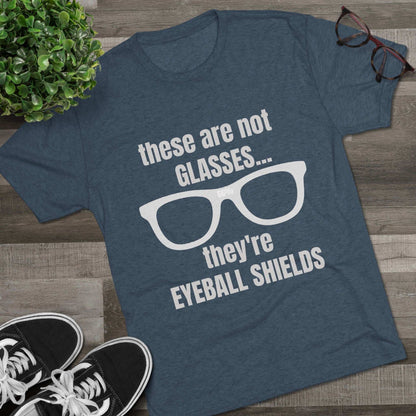 Light heather tri-blend tee flat-laid, printed with glasses graphic and text ‘these are not GLASSES... they’re EYEBALL SHIELDS.