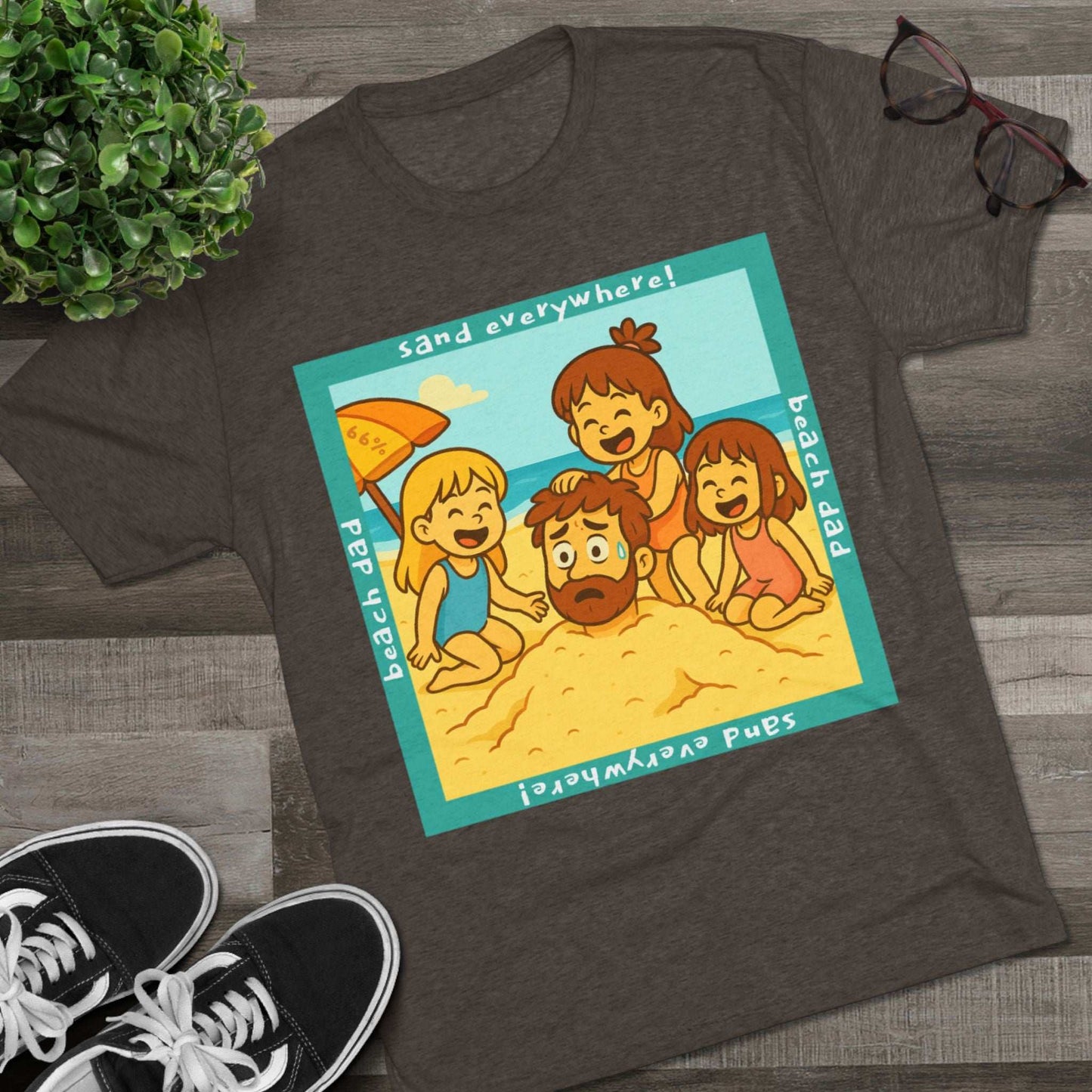 “Beach Dad Buried 66% Tri-Blend Tee — graphic tee flat-lay, cartoon dad sand-buried under umbrella, three kids playing, teal ‘sand everywhere!’ square border, ‘beach dad’ text, unisex casual style.