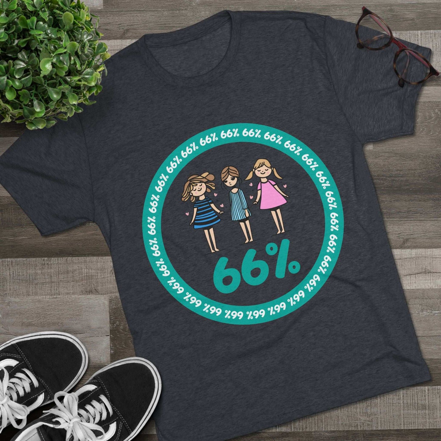 Flat-lay of tri-blend tee with three cartoon girls inside a teal 66% circle and repeating 66% border