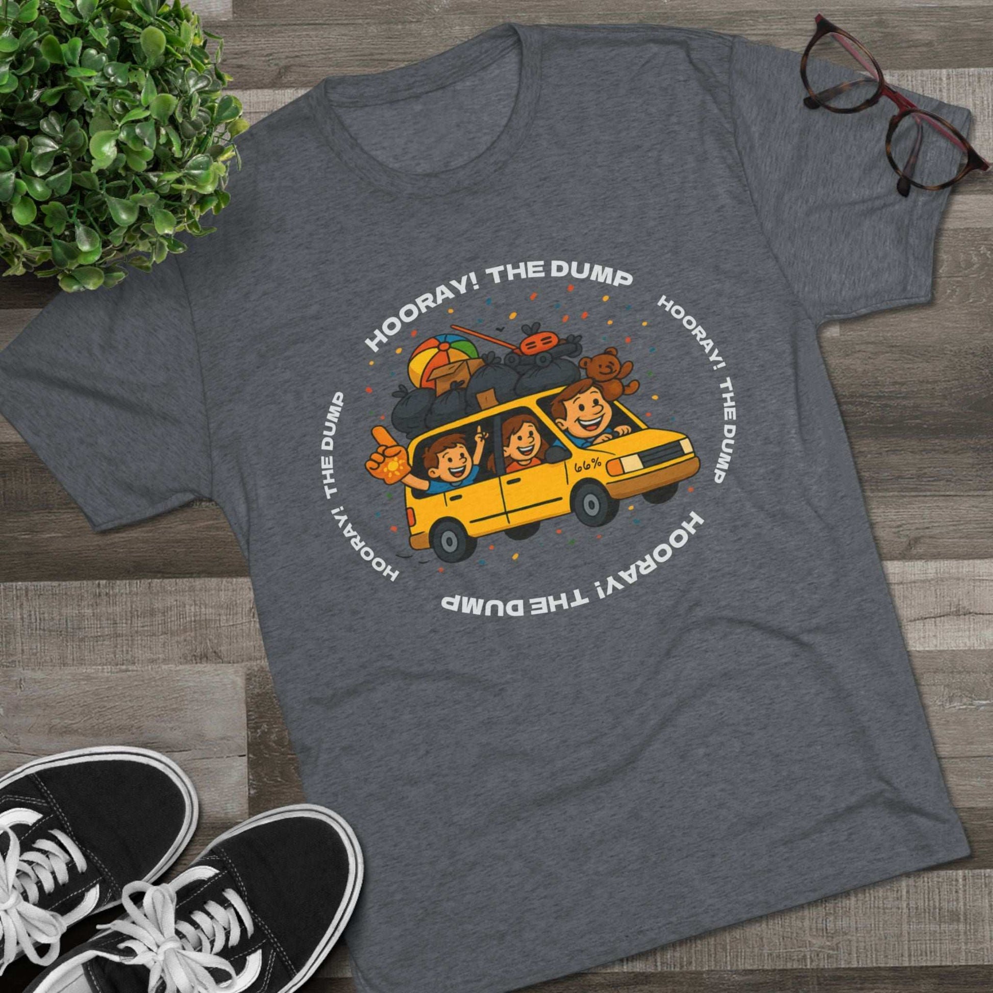 Cartoon yellow “66%” minivan T-shirt design with roof piled high in trash bags, lawnmower and beach ball, plus a dad driving and two excited kids waving with confetti.