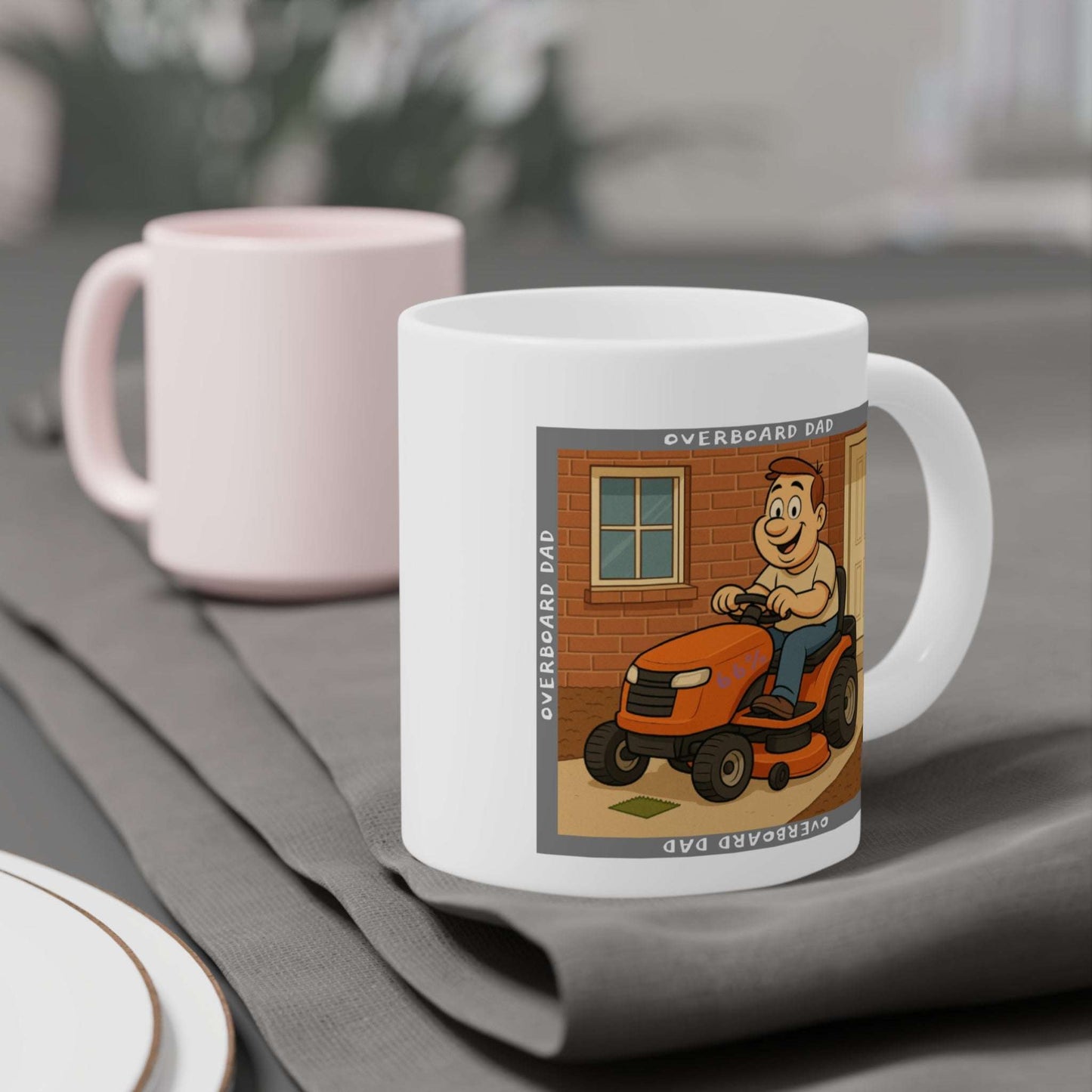 Graphic mug depicting a happy dad mowing the lawn on a ride-on tractor beside a brick wall and front door, encircled by the phrase ‘Overboard Dad’ in a repeating border.