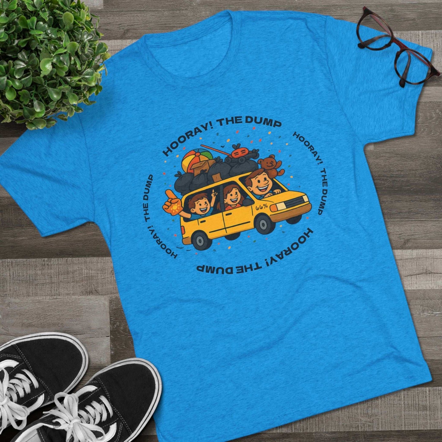 Cartoon yellow “66%” minivan T-shirt design with roof piled high in trash bags, lawnmower and beach ball, plus a dad driving and two excited kids waving with confetti.