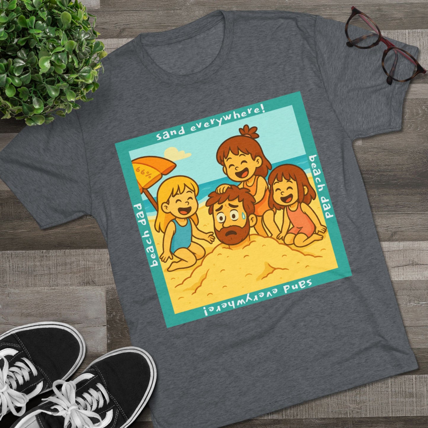 “Beach Dad Buried 66% Tri-Blend Tee — graphic tee flat-lay, cartoon dad sand-buried under umbrella, three kids playing, teal ‘sand everywhere!’ square border, ‘beach dad’ text, unisex casual style.