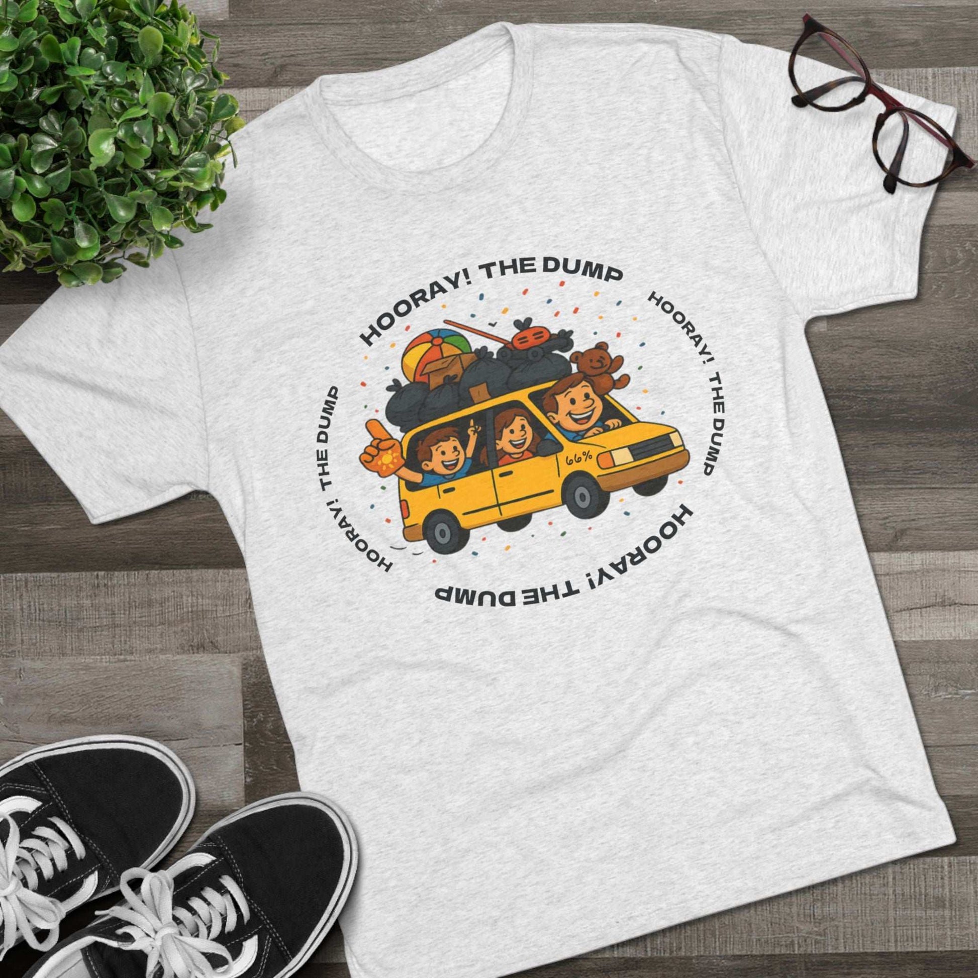 Cartoon yellow “66%” minivan T-shirt design with roof piled high in trash bags, lawnmower and beach ball, plus a dad driving and two excited kids waving with confetti.