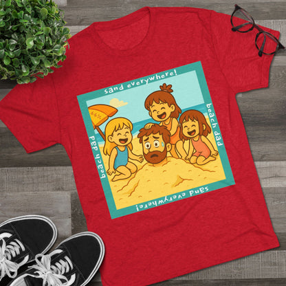 “Beach Dad Buried 66% Tri-Blend Tee — graphic tee flat-lay, cartoon dad sand-buried under umbrella, three kids playing, teal ‘sand everywhere!’ square border, ‘beach dad’ text, unisex casual style.