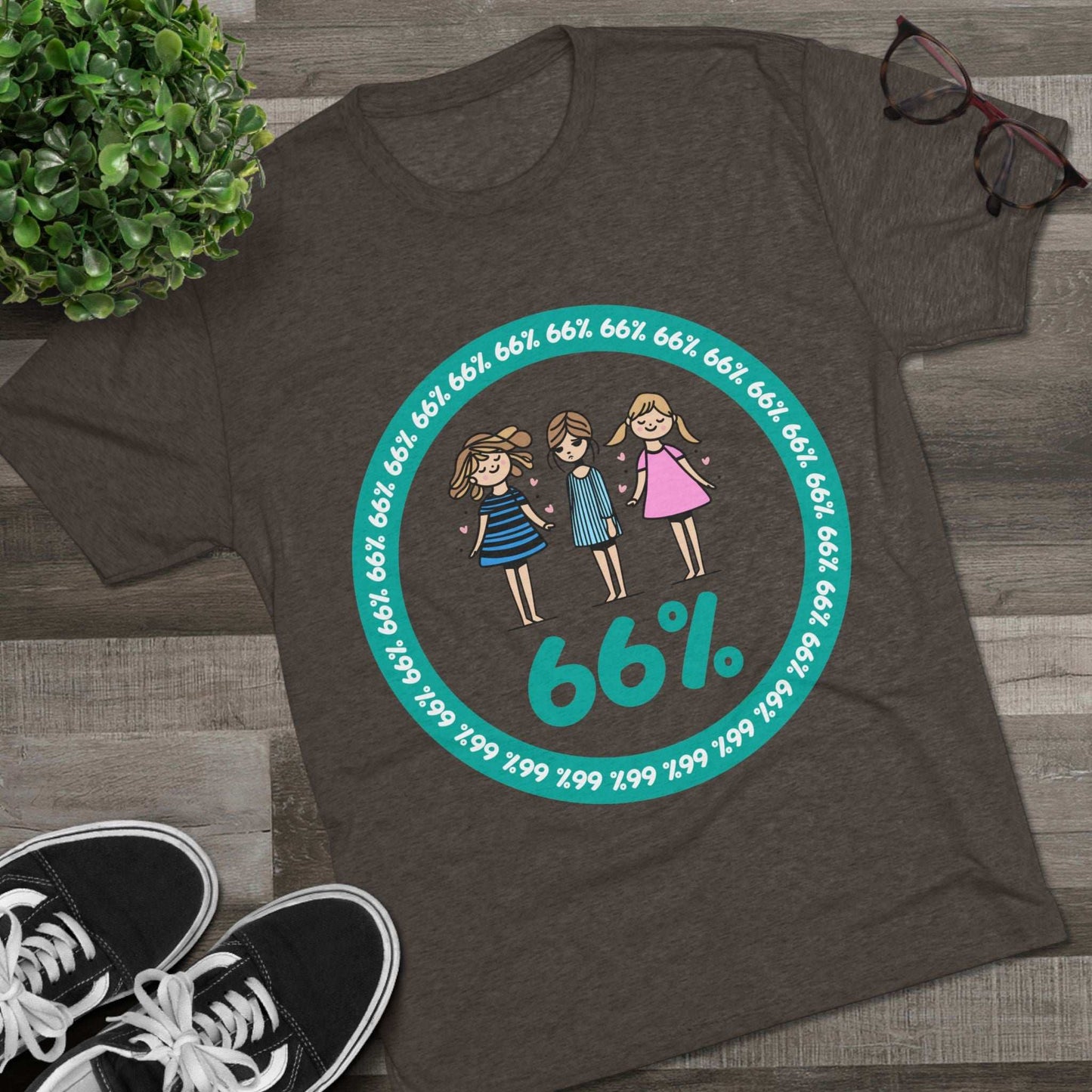 Flat-lay of tri-blend tee with three cartoon girls inside a teal 66% circle and repeating 66% border