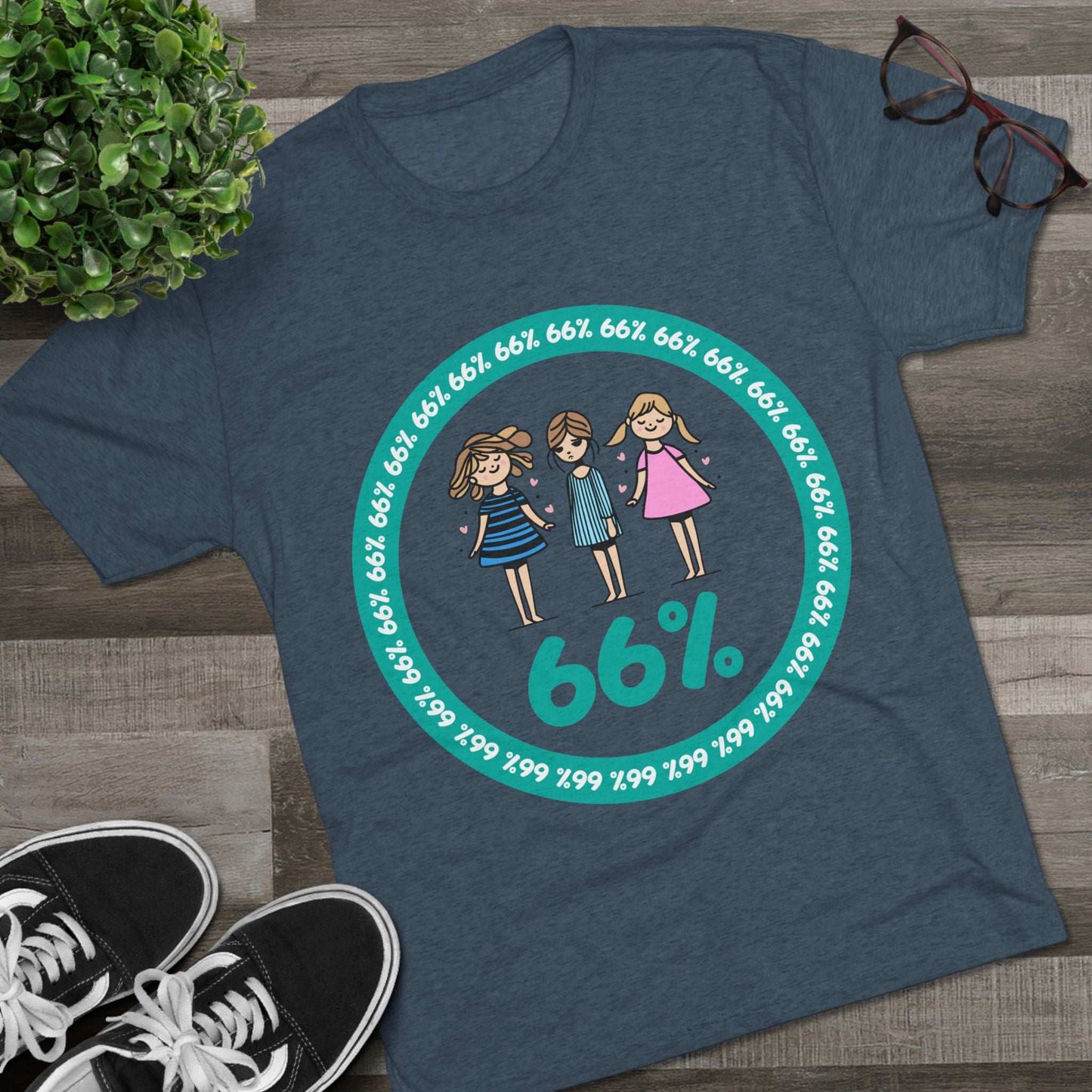 Flat-lay of tri-blend tee with three cartoon girls inside a teal 66% circle and repeating 66% border
