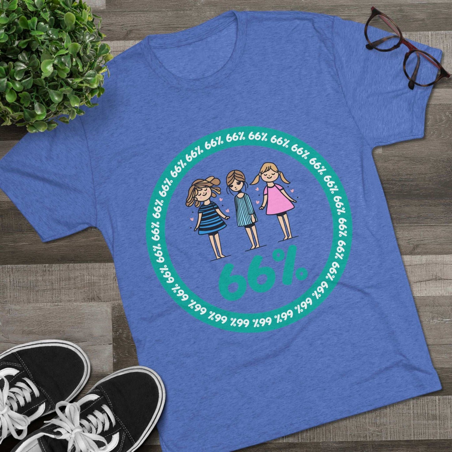 Flat-lay of tri-blend tee with three cartoon girls inside a teal 66% circle and repeating 66% border