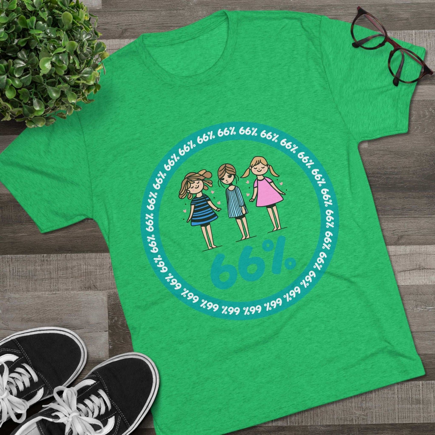 Flat-lay of tri-blend tee with three cartoon girls inside a teal 66% circle and repeating 66% border
