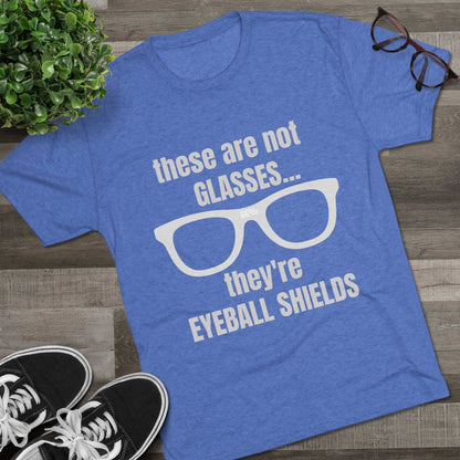 Light heather tri-blend tee flat-laid, printed with glasses graphic and text ‘these are not GLASSES... they’re EYEBALL SHIELDS.