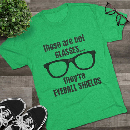 Light heather tri-blend tee flat-laid, printed with black glasses graphic and text ‘these are not GLASSES... they’re EYEBALL SHIELDS.
